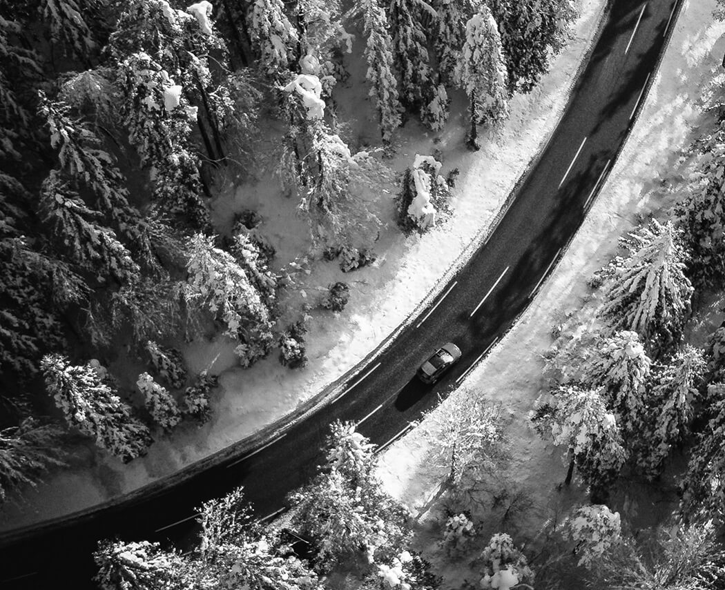 Car driving on a snowy road in a winter landscape.