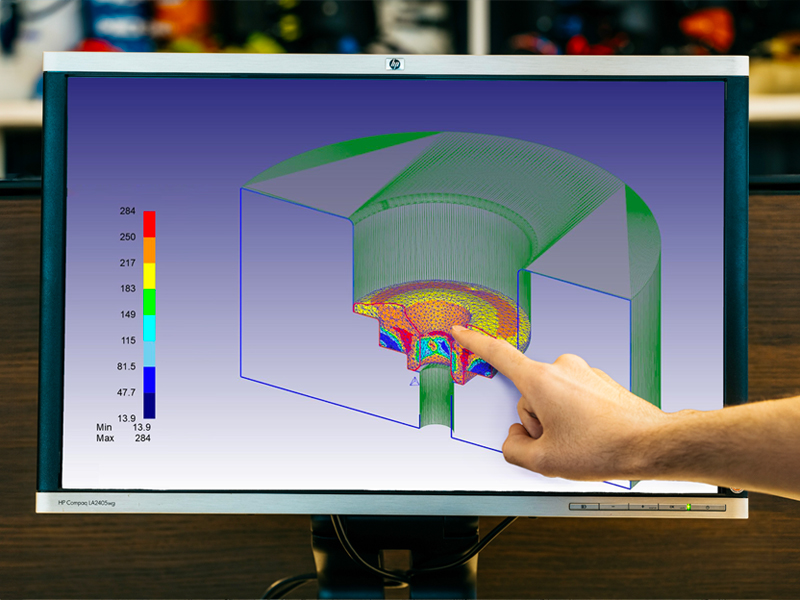 Technician pointing to a 3D model with finite element analysis (FEA) displayed on a monitor